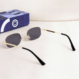 Sunglasses with gold frame and black arms on a white surface with a blue box in the background.
