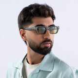 Male model wearing Milestone Green Square Sunglasses by Sunglassic. Featuring bold square frames in a muted green shade with tinted lenses, styled with a mint green shirt and neutral background.