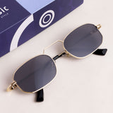 Gold-framed sunglasses with dark lenses on a white surface, with a branded box in the background.
