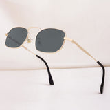 Sunglasses with gold frame and dark lenses on a light background