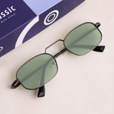 Sunglasses with green lenses on a white surface next to a blue box.