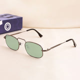Sunglasses with green lenses on a light beige surface with a blue box in the background